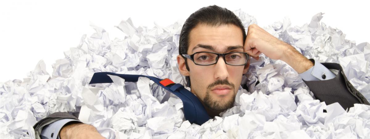 man under stacks of paper